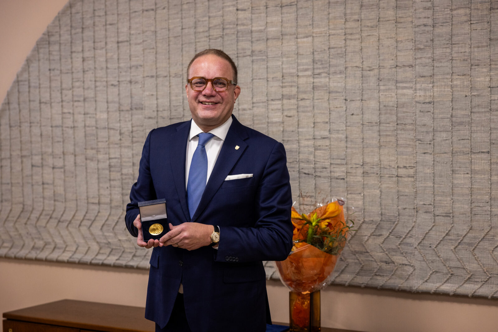 Mies pitelee mitalia kädessään