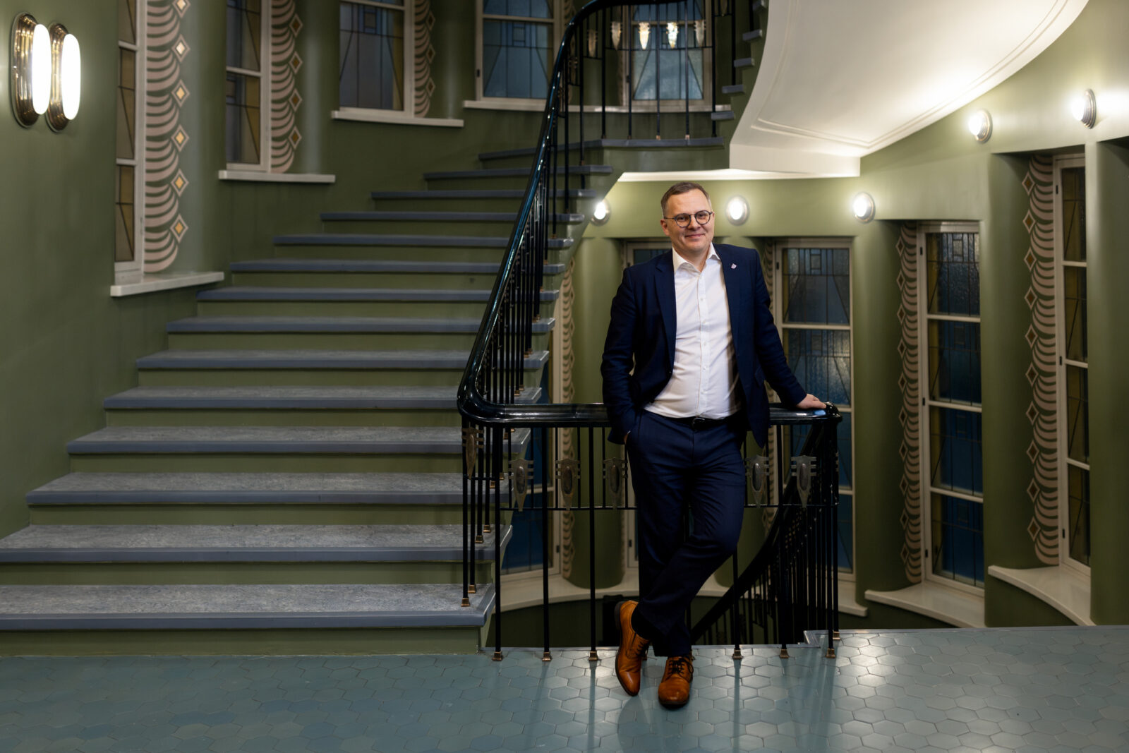 Henkilö seisoo ja nojaa kaiteeseen Lahden kaupungintalon portaikossa.