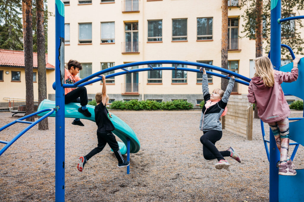 Kiipeilytelineessä kiipeileviä lapsia koulun pihassa