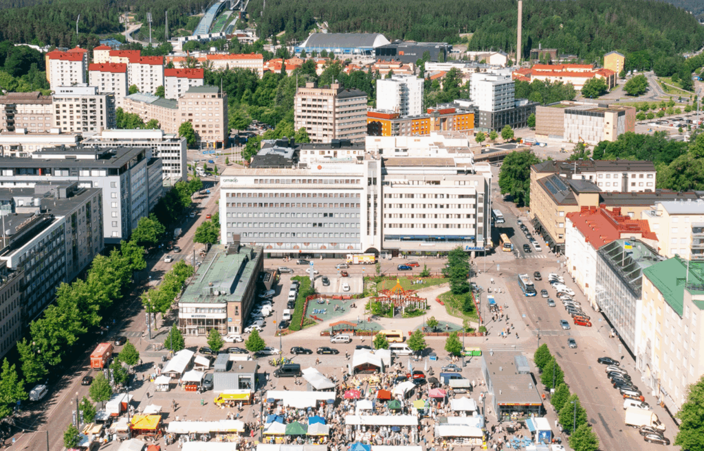 Ilmakuva Lahden kauppatorin ja Alatorin alueesta. Aurinkoisessa säässä alla levittyvät kuukausimarkkinat värikkäine kojuineen.